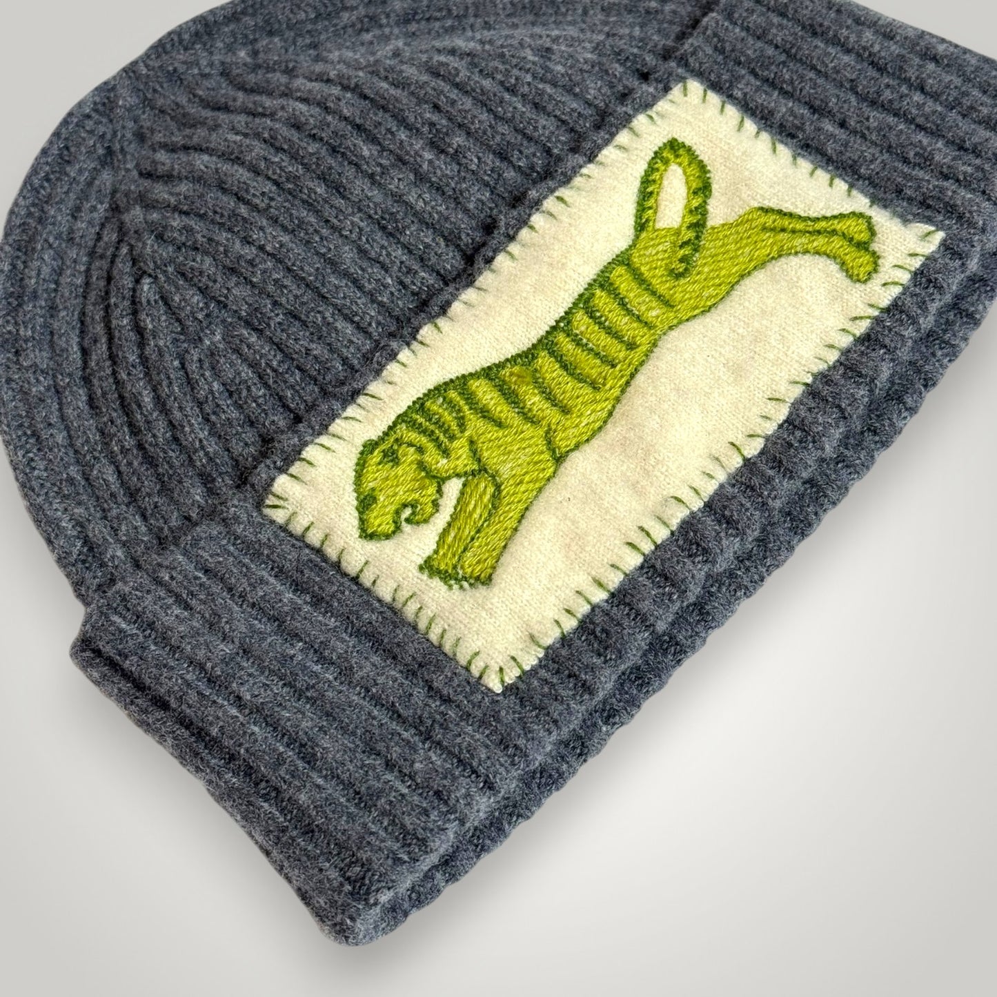 etail of green tiger embroidery on luxury merino wool winter hat with blanket stitch border