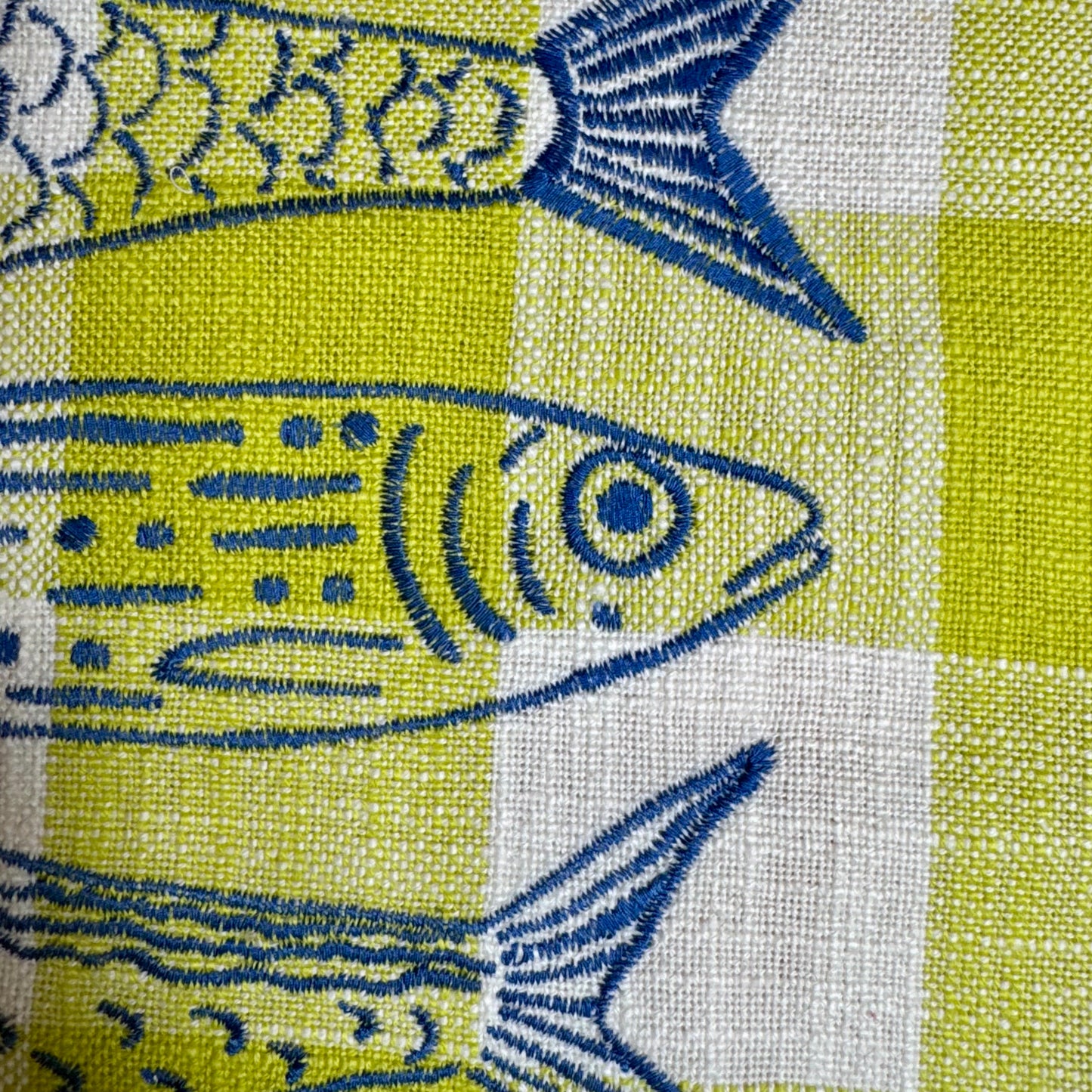 Close-up of hand-drawn fish embroidery in blue thread on citron and cream plaid cotton tea towel