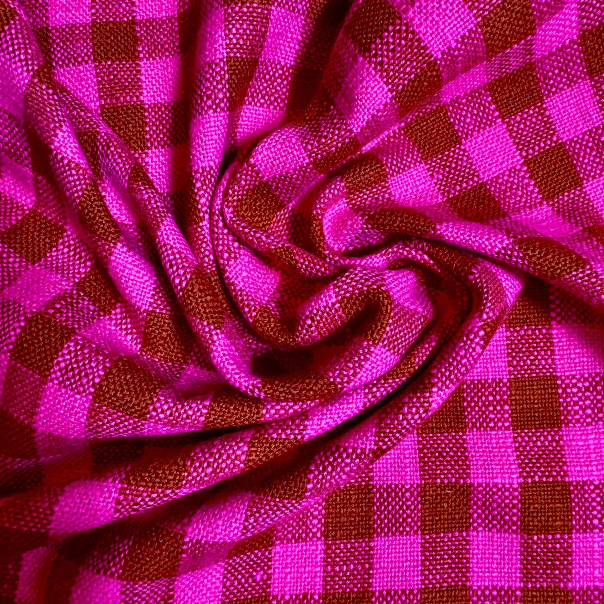 Close-up of bold fuchsia and cocoa gingham cotton fabric folds showing thick slubbed weave