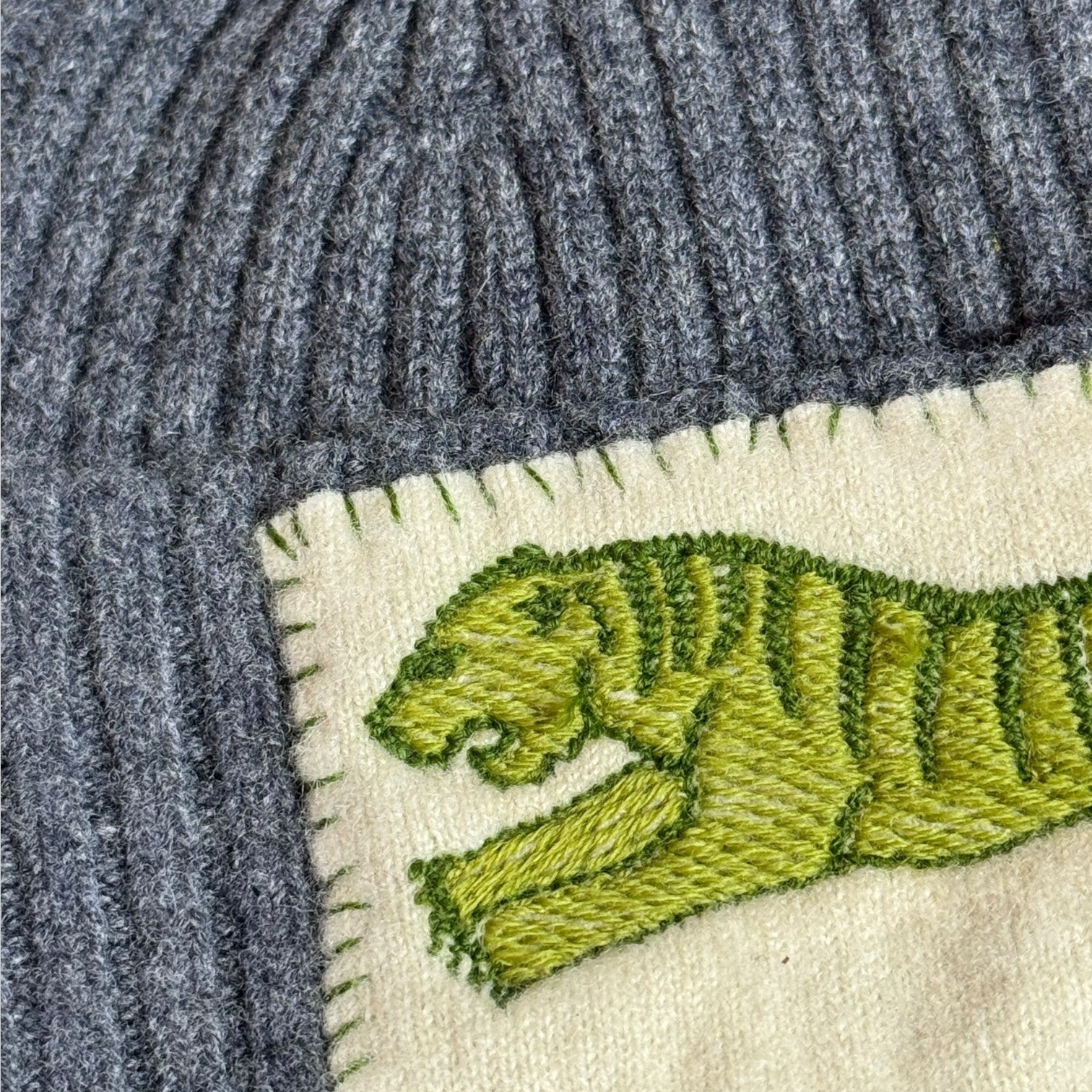 Heathered charcoal ribbed wool beanie with tiger embroidery patch, angled side view