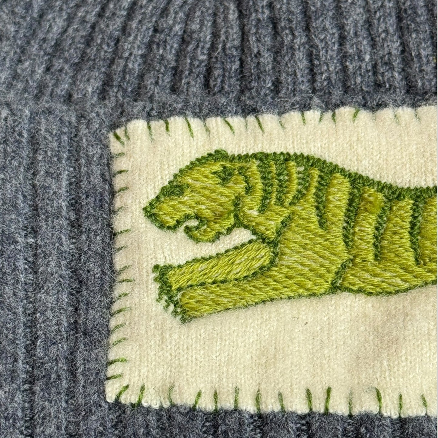 Close up of embroidered tiger design on cashmere patch showing green striped tiger detail