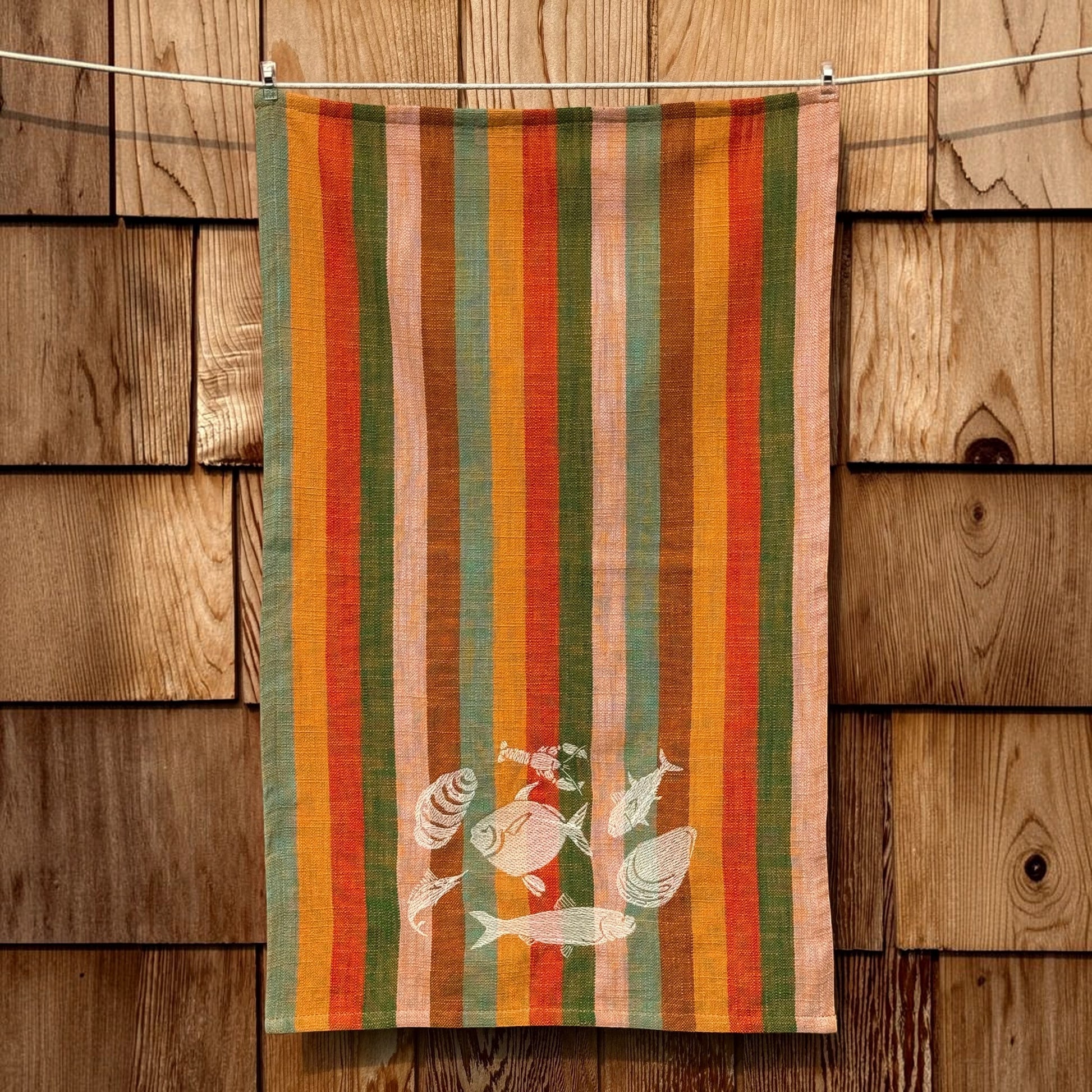 Full-length view of striped coastal grandmother tea towel with cream embroidered sea life design near the bottom hem