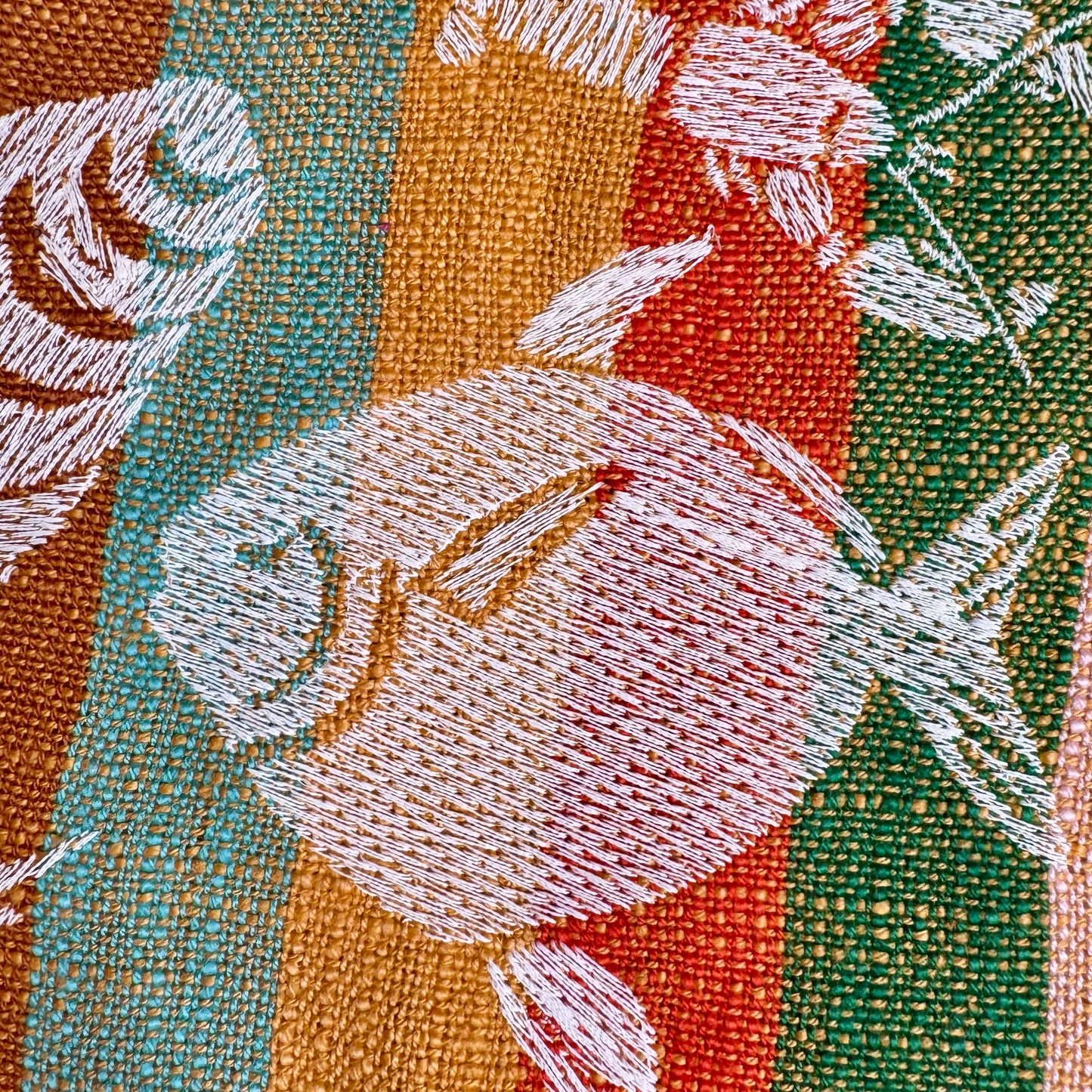 Close-up of hand-drawn fish, shell, and crab embroidery in cream thread on striped cotton tea towel