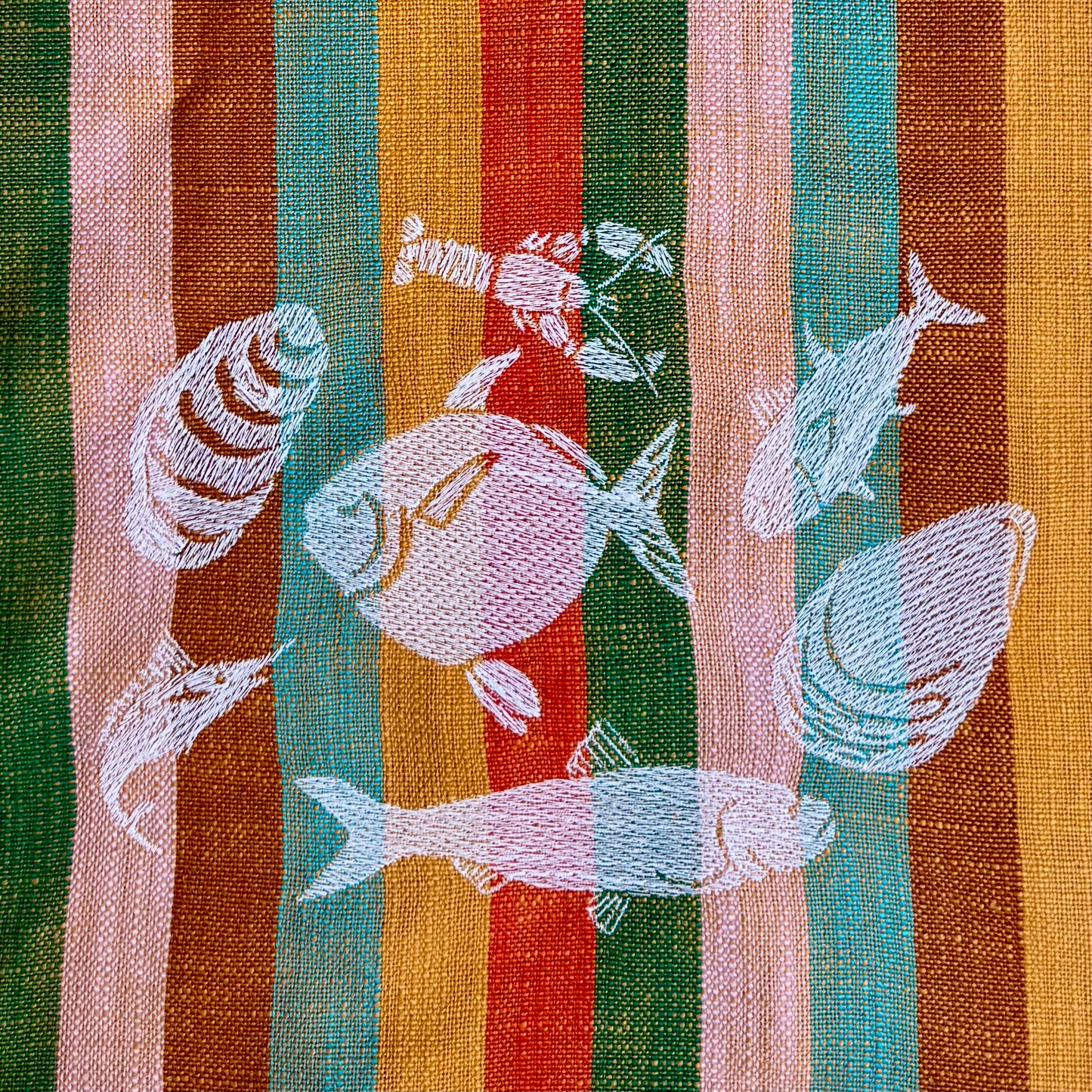 Macro view of cream embroidery stitching detail on coastal grandmother tea towel design
