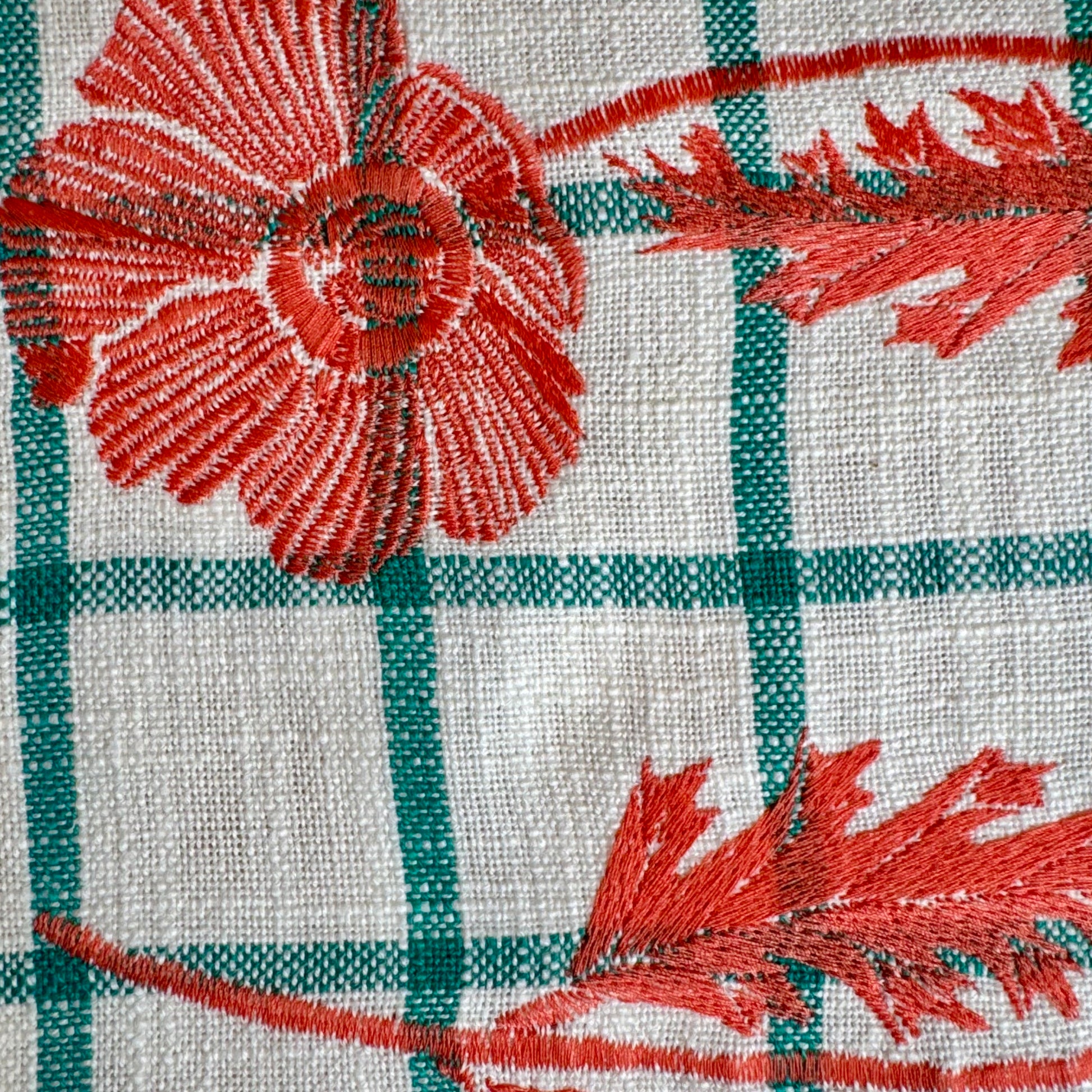 Close-up of hand-drawn orange poppy embroidery on cream and turquoise windowpane plaid cotton tea towel