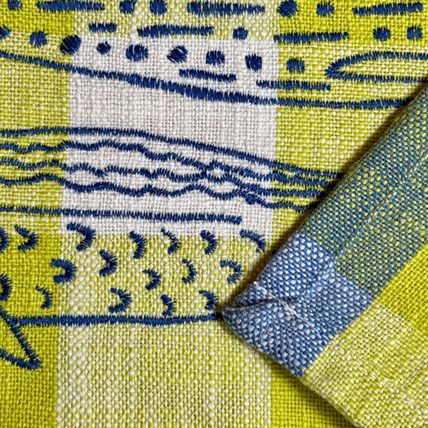 Macro view of blue embroidery stitching detail on fish design with plaid tea towel hem