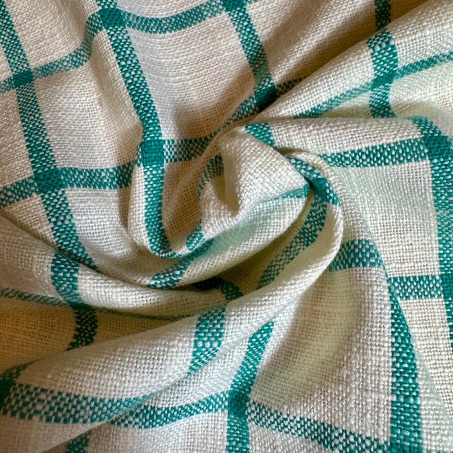 Close-up of turquoise windowpane plaid cotton fabric folds showing thick slubbed weave