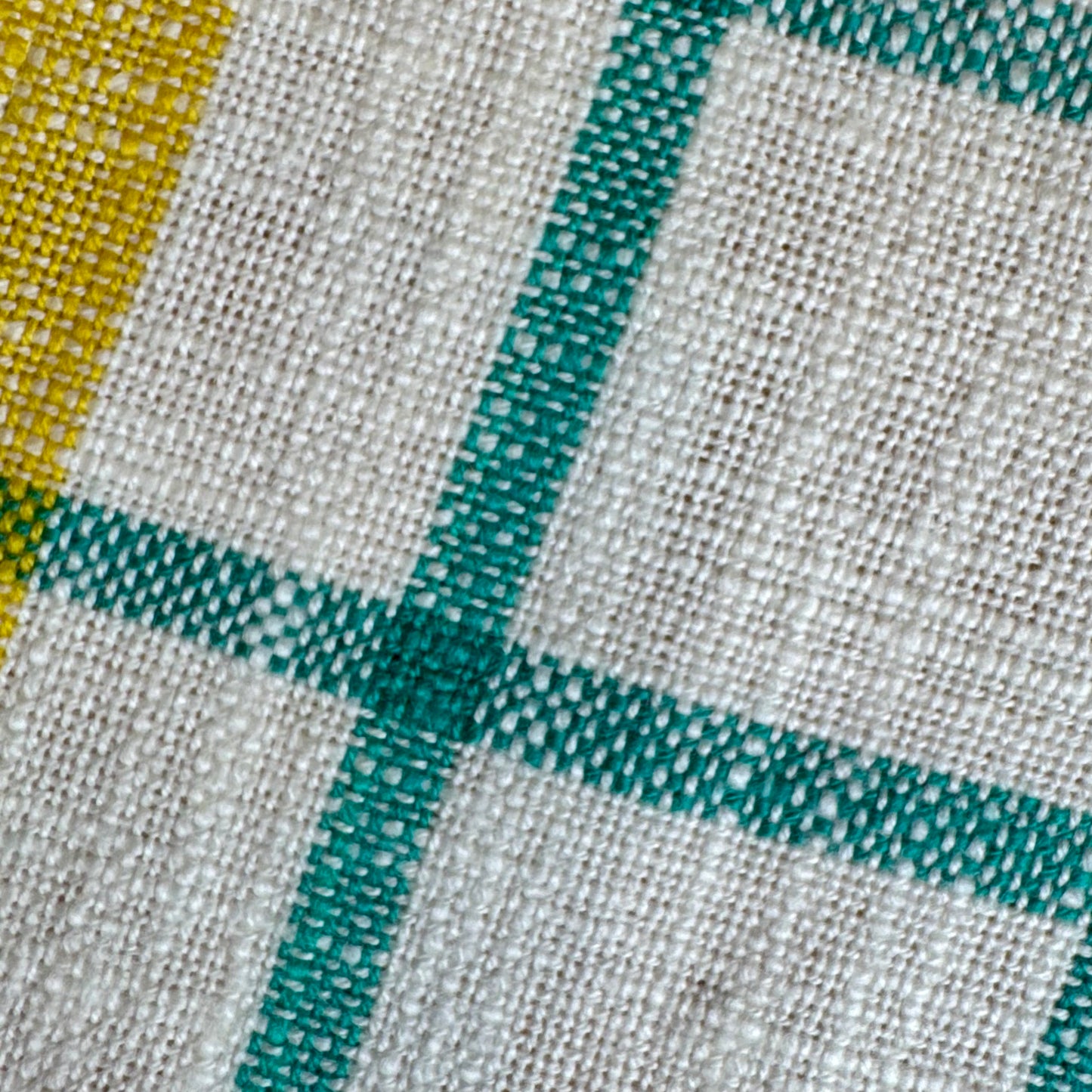 Macro detail of cream and turquoise windowpane plaid cotton toweling fabric with yellow selvedge